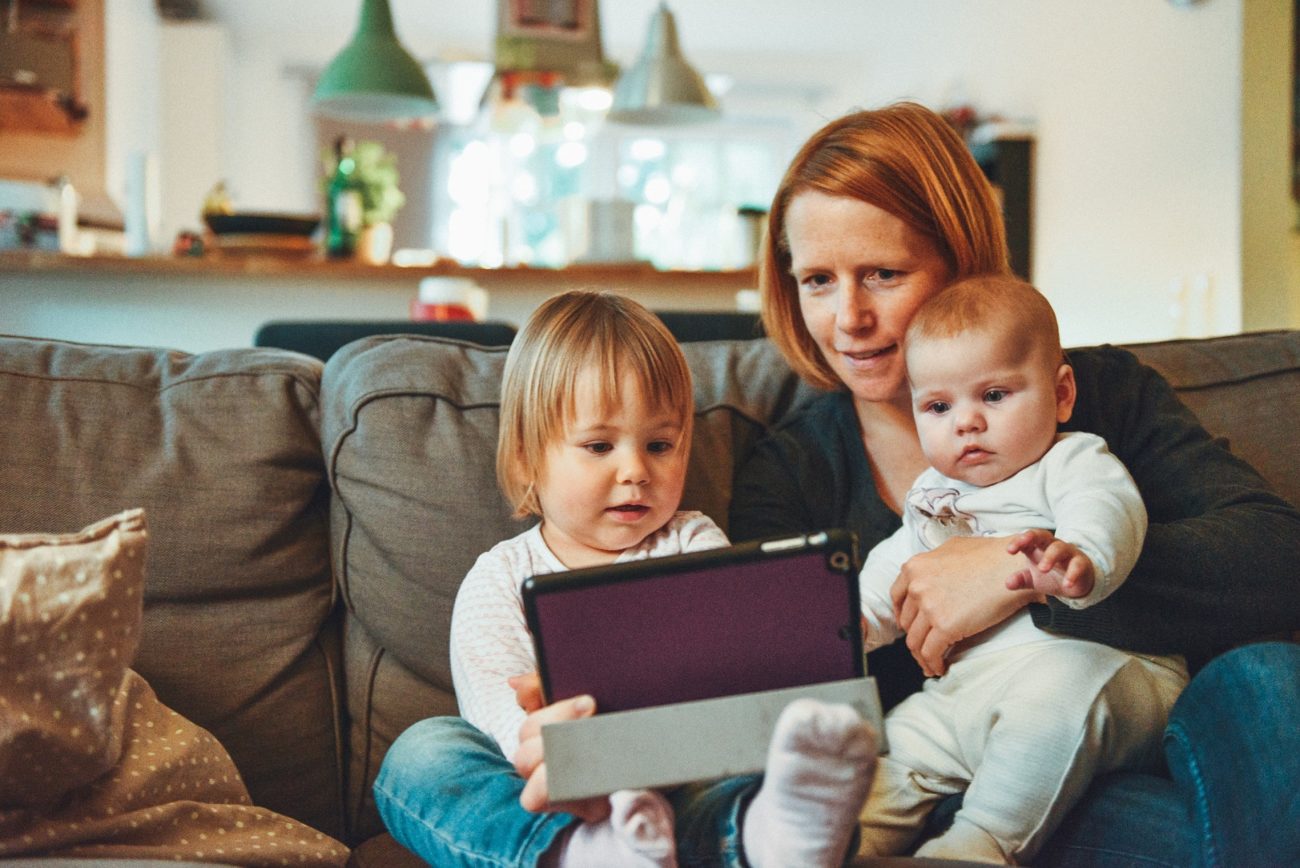 mama s dvoma detmi sediaca na gauci drzi tablet