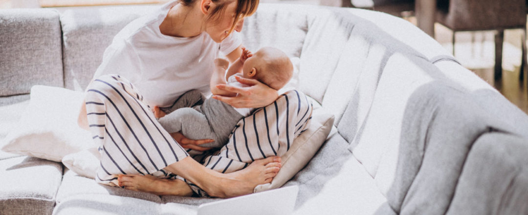 Mama sediaca v tureckom sede na gauči s bábätkom v náručí