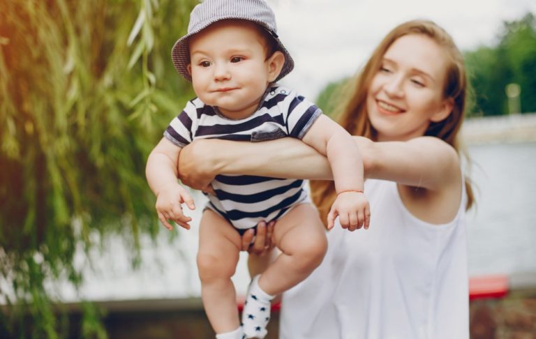 vitamín D a bábätká, opaľovanie bábätiek, mama držiaca chlapčeka v bodyku a klobúčiku