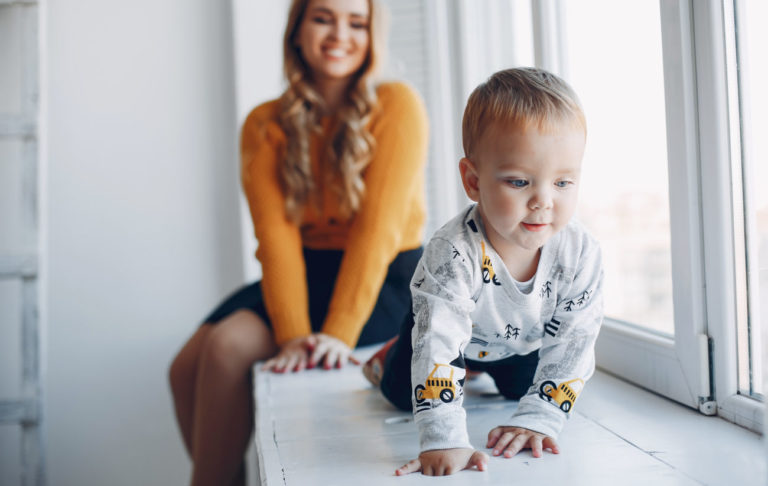 Mama sediaca pri okne so synom loziacim po parapate