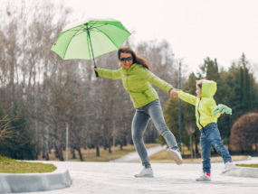 Mamina so dáždnikom sa drží za ruku s dieťaťom v parku