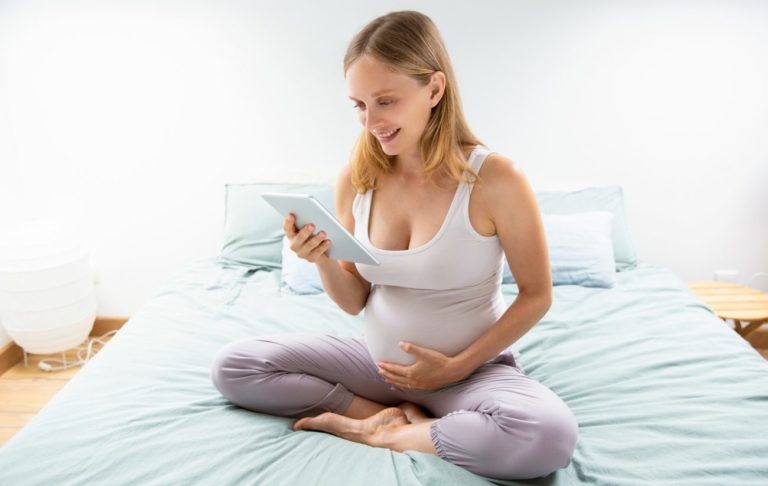 príprava na pôrod v čase koronavírusu, tehotná žena s tabletom na posteli