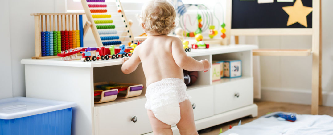 Dieťatko v plienke kráča k hračkám v detskej izbe