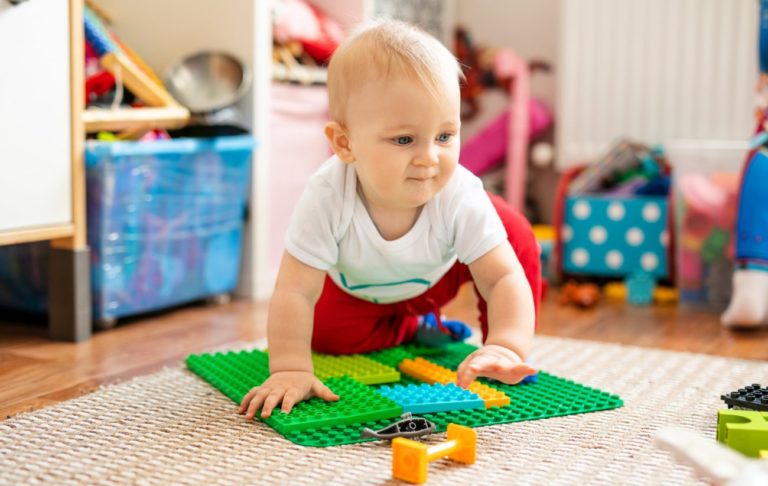 Pohybové aktivity s deťmi, štvornožkujuci chlapec na koberci s legom