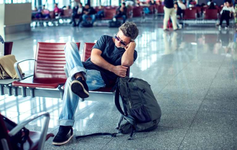 muž čakajúci na odlet na letisku