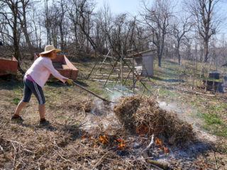 žena páli suchú trávu a konáre