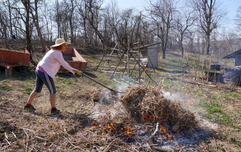 žena páli suchú trávu a konáre