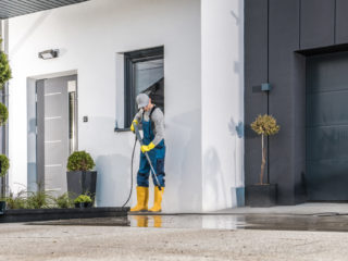 muž čistiaci vapkou okolie domu