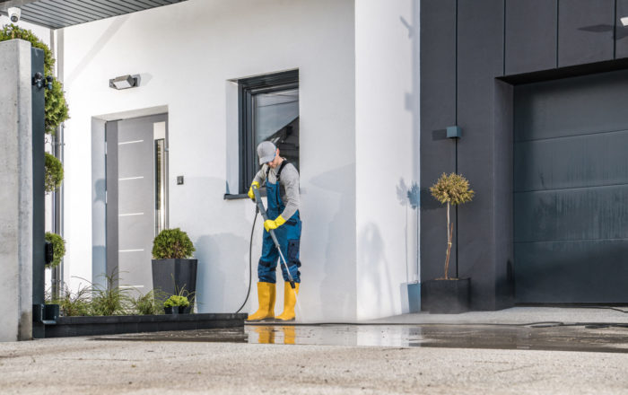 muž čistiaci vapkou okolie domu