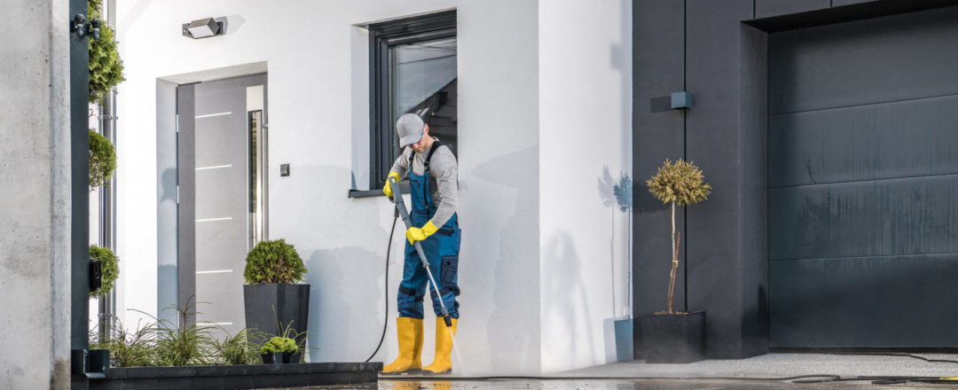 muž čistiaci vapkou okolie domu