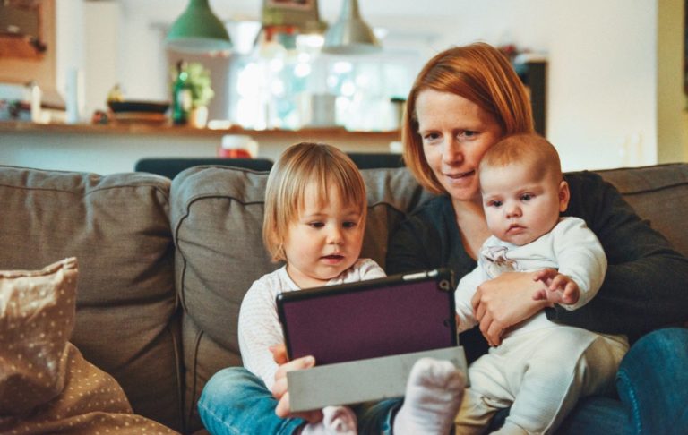 mama s dvoma detmi sediaca na gauci drzi tablet