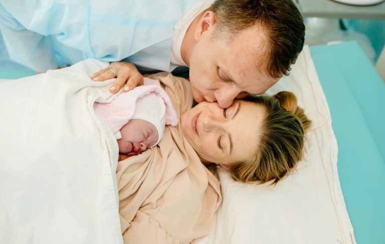 Portrait of happy couple after the delivery of their baby. Family in hospital together.