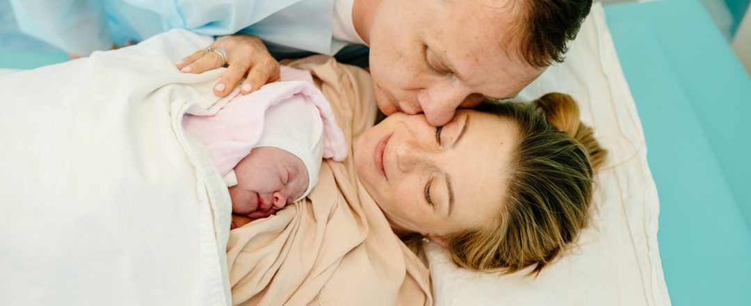 Portrait of happy couple after the delivery of their baby. Family in hospital together.