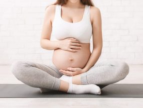 Pregnancy and active lifestyle. Young pregnant woman caring her belly, sitting on floor after doing sports, panorama